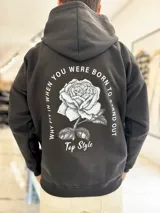Canguro negro de corte oversize con capucha y gran estampa en la espalda de una rosa acompañada por la frase "Why fit in when you were born to stand out" y el texto "Top Style".