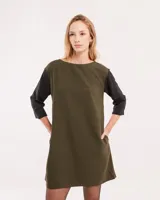 Vestido corto negro con mangas 3/4 verdes, cuello bote y bolsillos laterales.