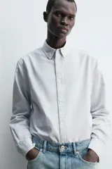 Camisa de corte regular fit confeccionada en tejido de algodón con diseño de rayas finas. Presenta cuello solapa, cierre frontal de botones y manga larga con puños abotonados.