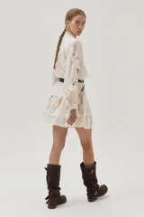 Falda corta de color blanco con diseño de doble volado y delicados bordados en tonos suaves que aportan movimiento y estilo.