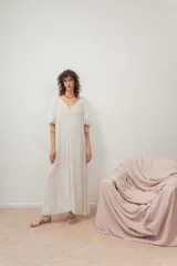 Vestido midi color blanco crudo, con escote en V, fruncido en el pecho y mangas cortas abullonadas.