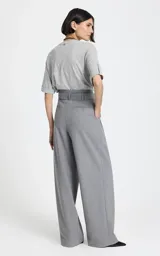 Pantalon sastrero de tiro alto en color gris, con diseño de pierna ancha y corte relajado. Presenta pliegues frontales, bolsillos laterales y un cinturón del mismo tejido para ajustar en la cintura.