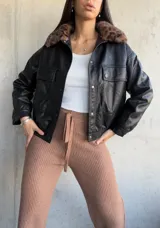 Campera negra de cuero sintético, con cuello de piel sintética con estampado animal print, cierre frontal con botones a presión, bolsillos con solapa en el pecho y corte recto.