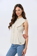 Musculosa de lino rayada con cuello mao y volados en los hombros. Presenta diseño de rayas verticales y aplique de etiqueta con logo en la parte posterior.