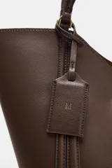 Bolso de hombro tipo maxi shopper, color beige claro, con pespuntes verticales en el cuerpo y doble asa. Incluye un bolso interior con cierre de cremallera metálica y cierre principal imantado.