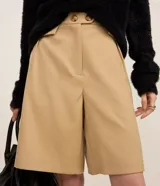 Bermuda de sastrería de corte recto y tiro alto, color beige. Cuenta con detalles de solapas plisadas y cierre con dos botones en la cintura.