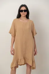 Vestido midi de lino color beige, con mangas cortas, cuello redondo, alforzas verticales en el pecho y detalle de volados en el ruedo.
