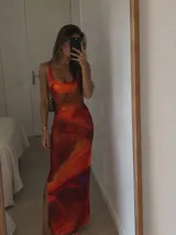 Vestido largo de microtul forrado, sin mangas, con escote redondo y diseño estampado en tonos cálidos anaranjados y rojizos con abertura lateral en la falda.