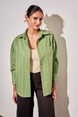 Camisa de corte oversize con estampado de rayas verticales en tonos verde, blanco y ocre. Presenta cuello clásico, cierre frontal con botones, bolsillo en el pecho y mangas largas con puños abotonados.