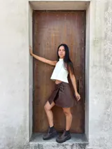 Minifalda tipo pareo confeccionada en cuero color chocolate, con diseño cruzado y cierre mediante tiritas laterales ajustables.