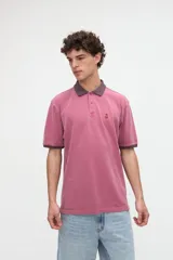 Remera polo de manga corta color rojo con efecto lavado, cuello y puños en contraste marrón. Cuenta con media cartera de botones, aberturas laterales en el dobladillo y un bordado pequeño de una estrella en el pecho.