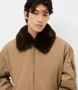 Campera bomber de sarga color tostado con cuello desmontable de pelo sintético oscuro. Presenta cierre frontal de cremallera, puños y cintura acanalados, y bolsillos laterales.