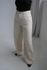 Jean de corte wide leg en color crudo, con tiro alto y costuras reforzadas en contraste. Presenta diseño de cinco bolsillos y cierre frontal con botón metálico.