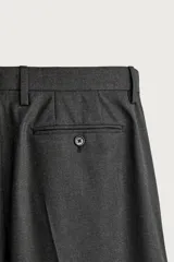 Pantalón de traje slim fit para hombre, color gris oscuro, con bolsillos frontales y bolsillos traseros de doble vivo con botón. Cuenta con cierre frontal de cremallera y botón, y presillas para cinturón.