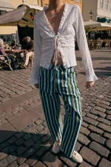 Top de manga larga con textura nido de abeja, escote en pico con detalle de volantes y cierre frontal mediante lazos ajustables.