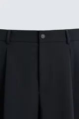 Pantalón de corte relajado en color verde militar, con diseño de pliegues frontales, bolsillos laterales y cierre de cremallera con botón.