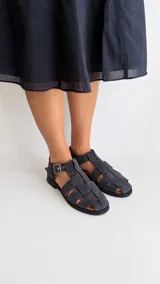 Sandalias cangrejeras de gamuza color marrón, con punta redonda, taco bajo, talonera cerrada y tira con hebilla metálica ajustable en el tobillo.