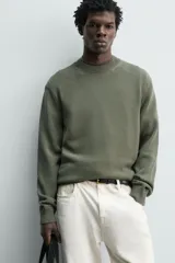 Sweater de punto negro de corte regular fit, confeccionado en algodón con cuello redondo, manga larga y acabados en rib.