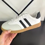 Championes deportivos de mujer, color blanco, con tres franjas laterales negras y talón negro. Suela de goma color caramelo.