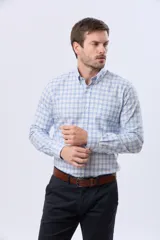 Camisa de manga larga con diseño a cuadros en tonos celeste, azul y blanco, con cuello abotonado y cierre frontal con botones.