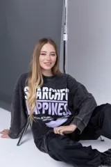 Buzo gris oscuro con estampa frontal con letras blancas y violetas.