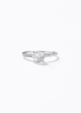 Anillo de plata 925 con engaste de cuatro puntas para una zirconia central redonda de 7mm. El cuerpo del anillo es delgado y está pavimentado con pequeñas zirconias a lo largo de la banda.