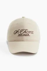 Gorra de sarga de algodón con efecto lavado, visera curva y bordado frontal con texto. Cuenta con trabilla ajustable con cierre de metal en la parte posterior.