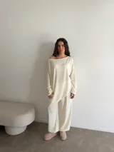 Buzo de punto color marfil, de diseño asimétrico oversize, manga larga y cuello redondo amplio.