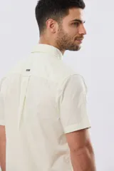 Camisa lisa de algodón azul marino, de manga corta, con cuello camisero, cierre frontal de botones y un bolsillo aplicado en el pecho.