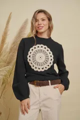Buzo de punto color negro con cuello redondo, mangas largas y detalle de mandala tejido en color crema en el frente.