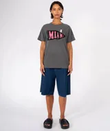 Remera color crudo con cuello redondo y manga corta. Estampado frontal de una banderín marrón con la palabra "BOSTON" en letras doradas con efecto glitter. Incluye dos pines decorativos prendidos en la zona superior derecha del pecho.