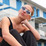 Lentes de sol con armazón ovalado de estilo retro en color negro y cristales oscuros. Presentan un detalle metálico en forma de estrella en las patillas.