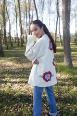 Maxi cardigan color crema de lana merino con bordado de flores rojas y azules.