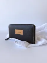 Billetera grande de cuero color negro, con cierre metálico y monedero interno.