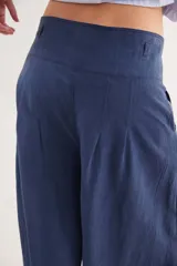 Pantalón de tiro alto en color azul, con cierre frontal de tres botones, pinzas en la cintura y corte holgado.