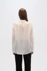 Camisa celeste de lyocell con textura arrugada, corte holgado, cuello clásico y cierre frontal con botones.