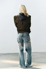 Jeans de tiro bajo y corte recto, color celeste con efecto lavado. Presenta diseño de doble tiro con detalle de short superpuesto con roturas, además de roturas adicionales en las perneras. Cuenta con cinco bolsillos, trabillas para cinturón y cierre frontal con cremallera y botón metálico.