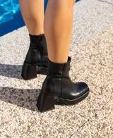 Botas cortas negras de cuero vacuno con textura tipo cocodrilo. Taco de madera forrado en cuero de 8cm, entre suela de goma de 2cm forrada en cuero, inclinación de horma de 6cm y caña de 15cm. Cierre YKK del lado interno y horma de punta cuadrada.