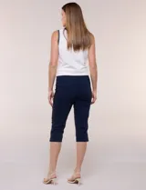 Pantalón capri blanco de tiro alto, corte entallado y silueta ajustada, con pretina ancha elastizada sin cierres, bolsillos simulados al frente y pequeños tajos en los ruedos.