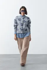 Cardigan de punto jacquard color gris con diseño floral en tono azul oscuro, de cuello redondo, manga larga y cierre frontal con botones.
