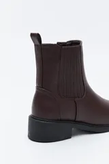 Bota tipo chelsea de caña baja, con laterales elastizados, tirador trasero y suela robusta.