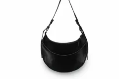 Cartera negra de cuero con forma de media luna, asa corta regulable y costuras blancas.