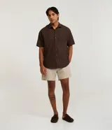 Camisa de corte relajado para hombre, confeccionada en una mezcla de cáñamo y algodón. Presenta cuello inglés, mangas cortas, cierre frontal con botones y un bolsillo de parche en el pecho con una pequeña etiqueta de la marca Ripping.