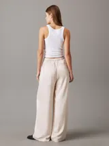 Pantalón de satén color crema, con cintura elástica, corte holgado y bolsillos laterales.