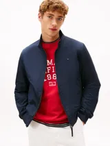 Campera tipo Harrington de Tommy Hilfiger en color azul marino, de corte amplio. Cuenta con cuello alto, cierre frontal de cremallera, bolsillos de ojal en la cintura y el pecho con el logo bordado.
