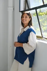 Chaleco de punto color celeste con escote en V, diseño trenzado en los laterales y terminaciones acanaladas en el ruedo y las sisas.