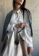 Camisa blanca de manga larga con detalles de encaje y calados verticales en el frente y las mangas.