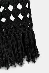 Vestido midi de crochet negro, sin mangas, con escote redondo y bajo terminado en flecos.