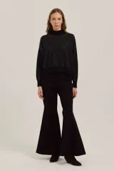 Sweater de punto negro con cuello alto y diseño de puntos brillantes en contraste. Presenta mangas largas con puños ajustados y un corte recto a la cintura.