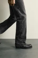 Jeans flare fit de denim de algodón en color celeste con lavado efecto desgastado. Presentan diseño de cinco bolsillos, tiro medio, cierre frontal con cremallera y botón, y bajo con acabado irregular.